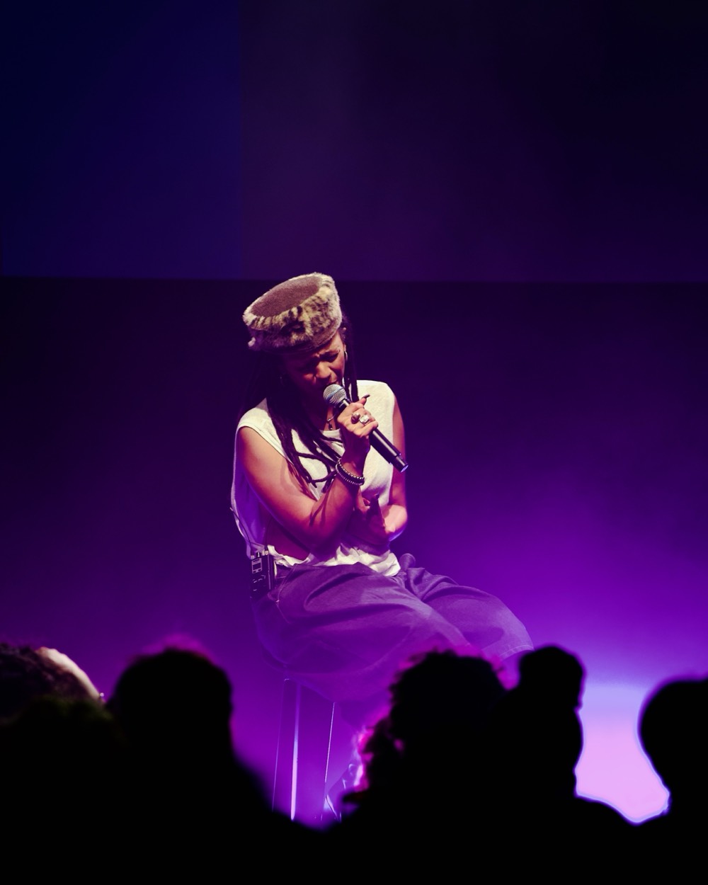 Chanteuse assise sur scène dans une lumière violette