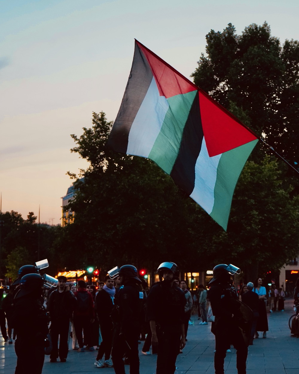 Manifestation à Paris : des drapeaux palestiniens au crépuscule, devant la ligne de policiers